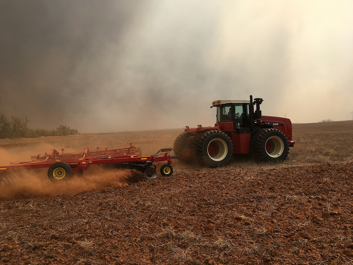 Tractor in a field with smoke in the sky