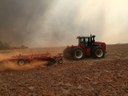 Tractor in a field with smoke in the sky